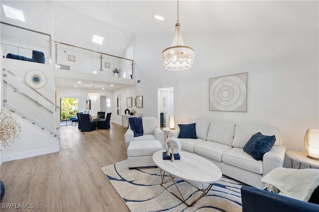 living room with an inviting chandelier, light hardwood / wood-style flooring, and high vaulted ceiling