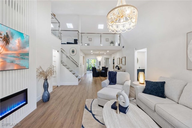 living room featuring an inviting chandelier, a towering ceiling, and light wood-type flooring