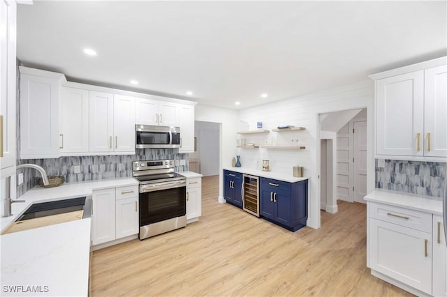 kitchen with blue cabinetry, wine cooler, sink, white cabinetry, and stainless steel appliances