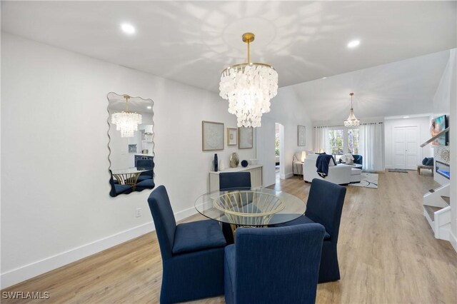 dining space featuring lofted ceiling, a notable chandelier, and light hardwood / wood-style floors