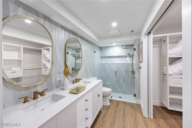 bathroom featuring tile walls, hardwood / wood-style floors, an enclosed shower, vanity, and toilet