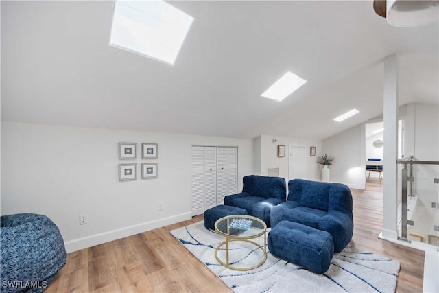 sitting room with lofted ceiling with skylight and light wood-type flooring