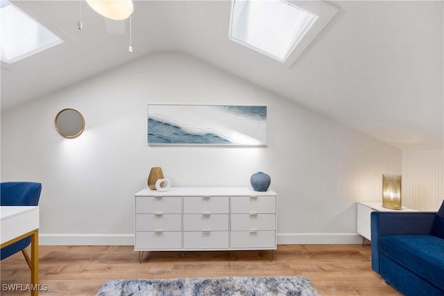 living area featuring vaulted ceiling with skylight and light wood-type flooring