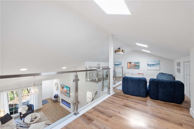 living room with lofted ceiling with skylight and light wood-type flooring