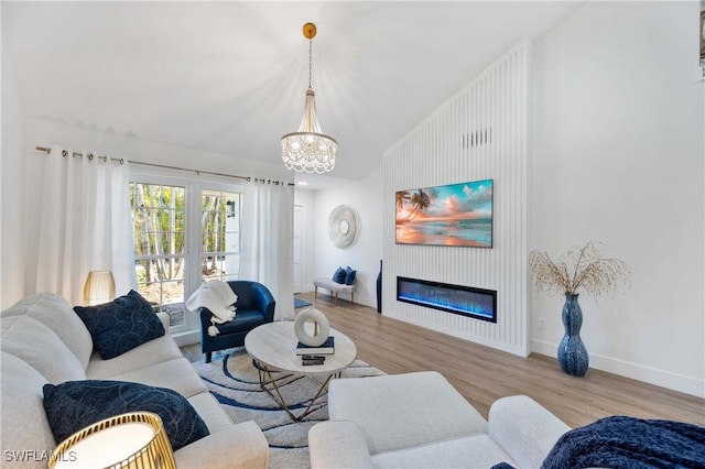 living room with vaulted ceiling, an inviting chandelier, and light hardwood / wood-style flooring