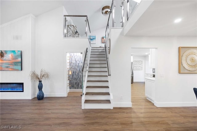 stairs with wood-type flooring and a towering ceiling