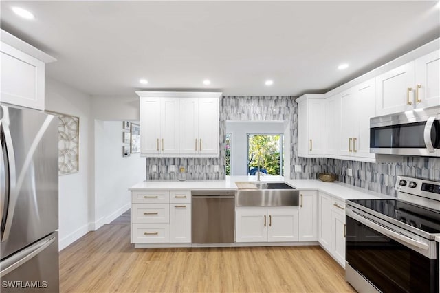 kitchen with white cabinetry, sink, light hardwood / wood-style floors, and appliances with stainless steel finishes