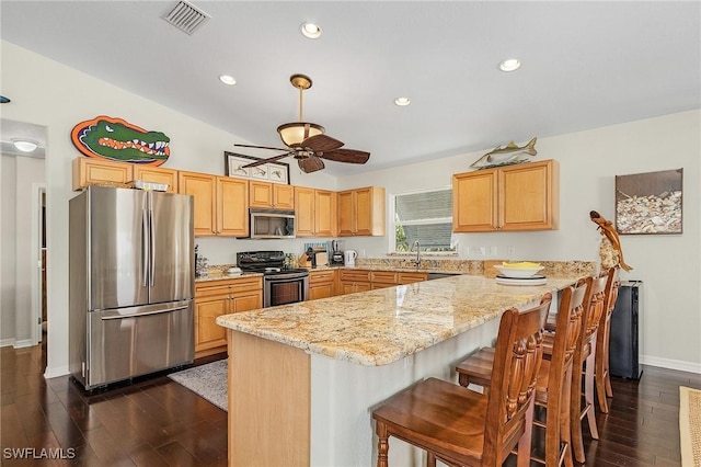 kitchen with sink, a breakfast bar area, appliances with stainless steel finishes, light stone counters, and kitchen peninsula