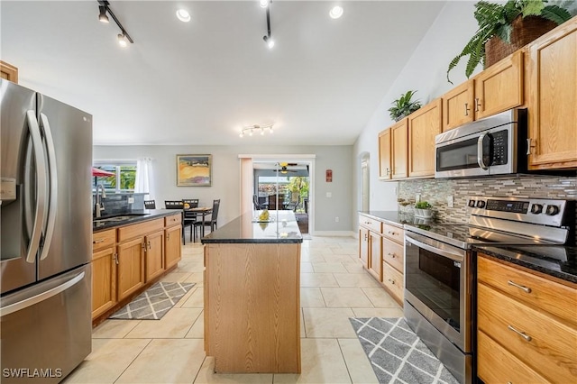 kitchen featuring light tile patterned flooring, backsplash, a center island, stainless steel appliances, and track lighting