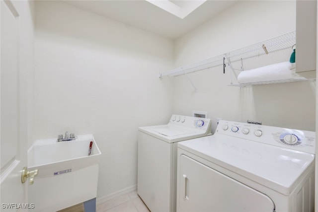 washroom with sink, light tile patterned floors, and washing machine and clothes dryer