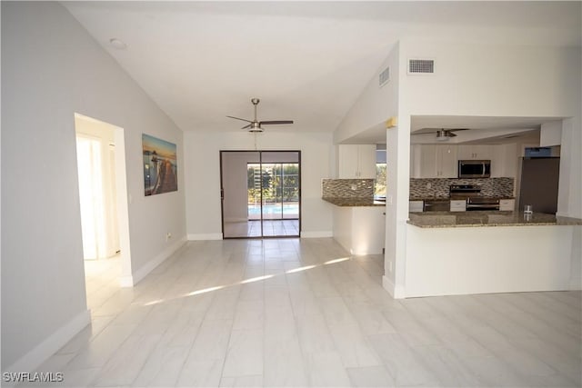 kitchen with ceiling fan, dark stone countertops, stainless steel appliances, white cabinets, and decorative backsplash