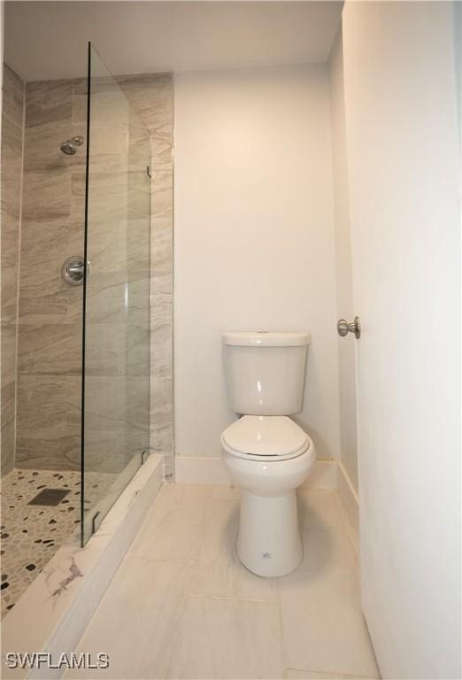 bathroom featuring a tile shower and toilet