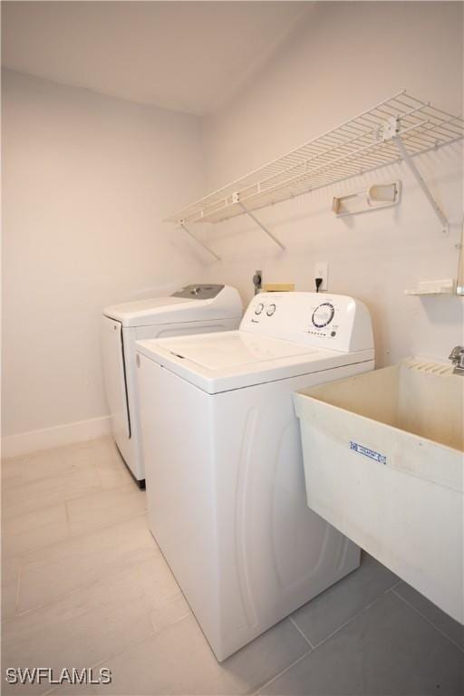 washroom with sink, washing machine and dryer, and light tile patterned floors