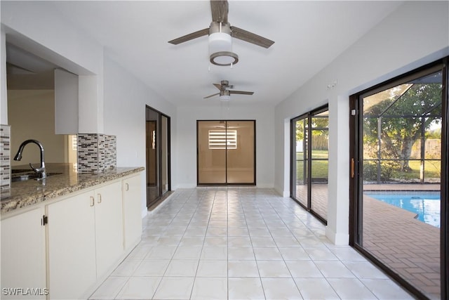 interior space with sink, light tile patterned floors, and ceiling fan