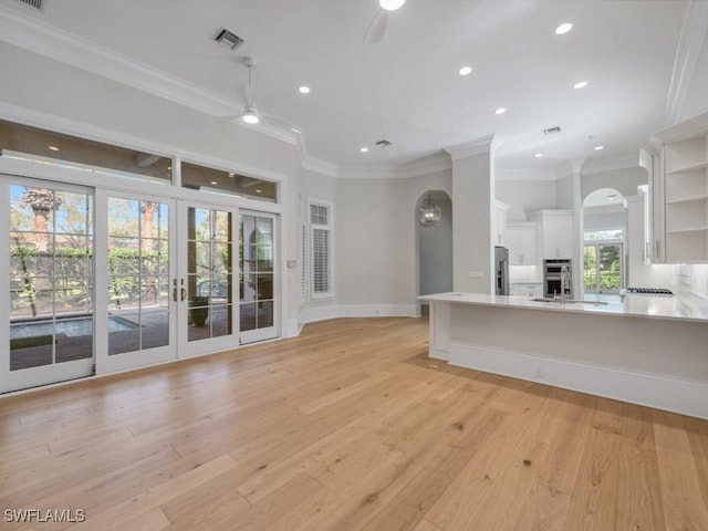 unfurnished living room featuring sink, crown molding, ceiling fan, light hardwood / wood-style floors, and french doors