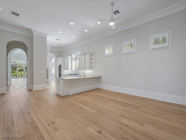 kitchen with plenty of natural light, kitchen peninsula, light hardwood / wood-style flooring, and white cabinets