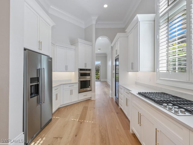 kitchen featuring white cabinetry, crown molding, light hardwood / wood-style floors, and appliances with stainless steel finishes