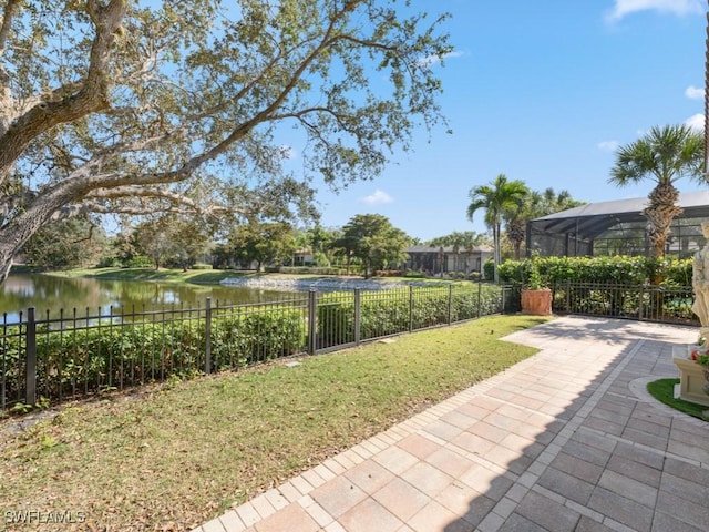 view of yard with a lanai, a patio area, and a water view