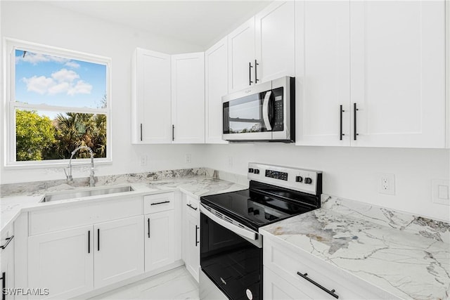 kitchen featuring stainless steel appliances, light stone countertops, sink, and white cabinets