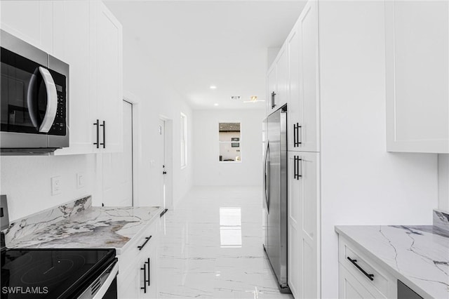 kitchen featuring a wealth of natural light, light stone countertops, white cabinets, and appliances with stainless steel finishes