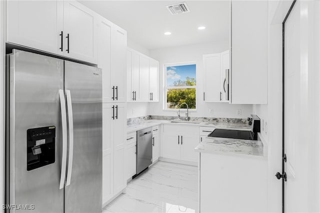 kitchen with appliances with stainless steel finishes, sink, white cabinets, and light stone counters