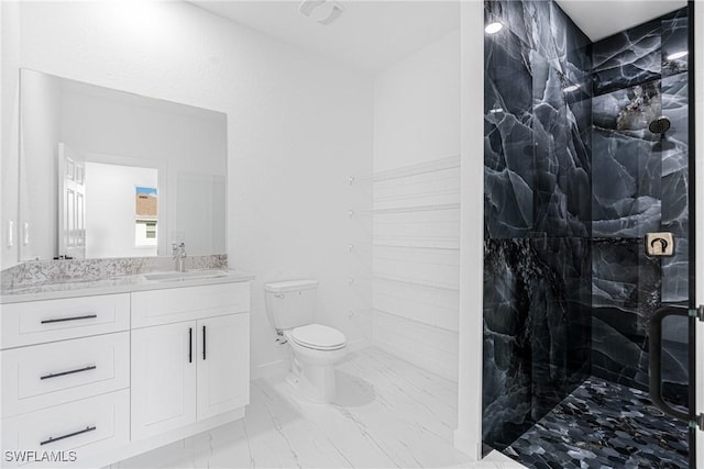 bathroom featuring vanity, toilet, and a tile shower