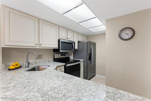 kitchen featuring light tile patterned flooring, stainless steel appliances, sink, and light stone counters