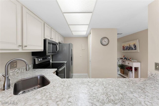 kitchen featuring white cabinetry, appliances with stainless steel finishes, light stone countertops, and sink