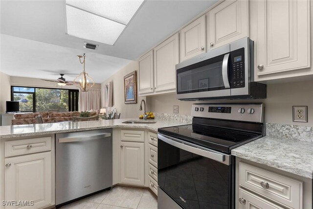 kitchen with stainless steel appliances, light tile patterned flooring, sink, and light stone counters