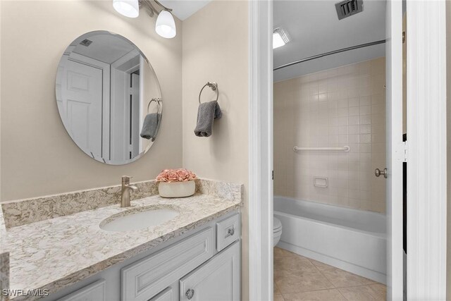 full bathroom featuring vanity, toilet, tiled shower / bath combo, and tile patterned flooring