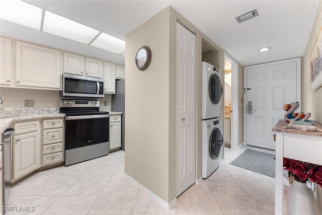 clothes washing area with stacked washer / dryer and light tile patterned floors