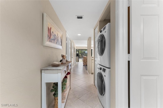 clothes washing area with stacked washer and dryer and light tile patterned flooring