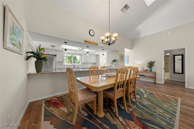 dining space featuring lofted ceiling, hardwood / wood-style floors, and a notable chandelier