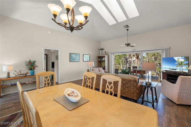 dining room featuring dark wood-type flooring, ceiling fan with notable chandelier, a skylight, and high vaulted ceiling