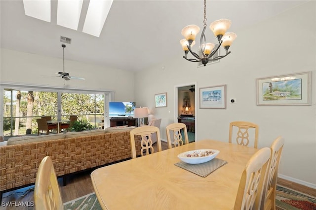 dining room with ceiling fan with notable chandelier, vaulted ceiling, and dark hardwood / wood-style floors