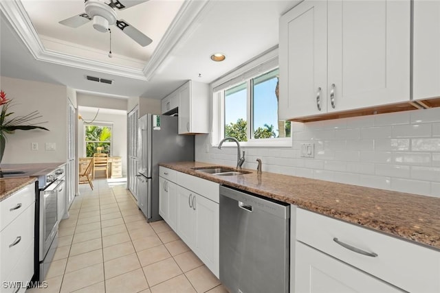 kitchen featuring appliances with stainless steel finishes, sink, white cabinets, and dark stone counters