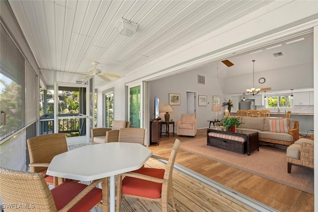 sunroom with vaulted ceiling, sink, and ceiling fan with notable chandelier