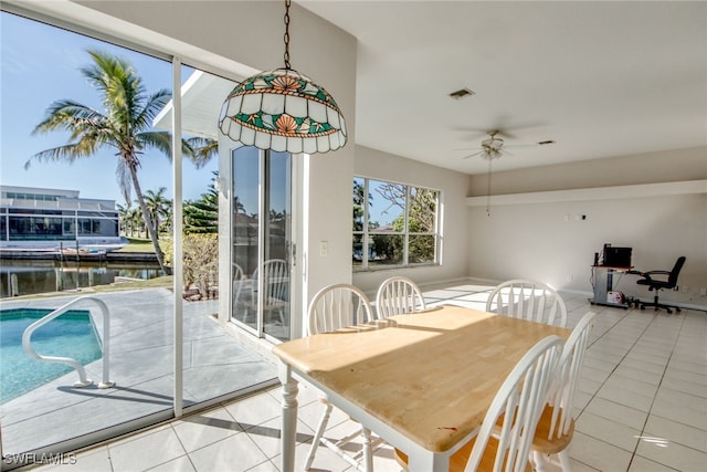 tiled dining room featuring a water view and ceiling fan