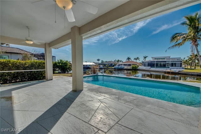 view of swimming pool with a patio, ceiling fan, and a water view