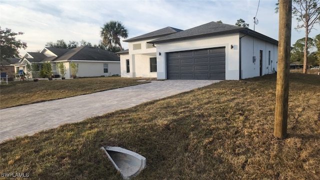 view of front of house with an attached garage, stucco siding, decorative driveway, and a front yard