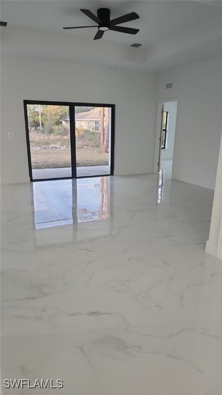 spare room with a ceiling fan, visible vents, and marble finish floor