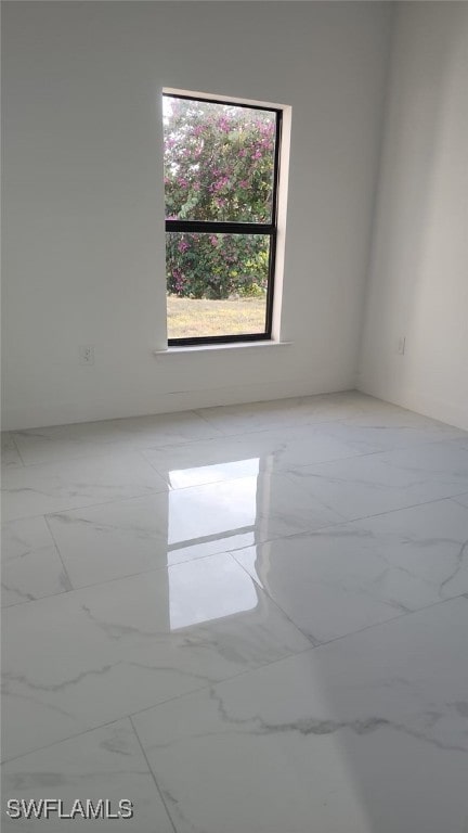 spare room with marble finish floor and a wealth of natural light