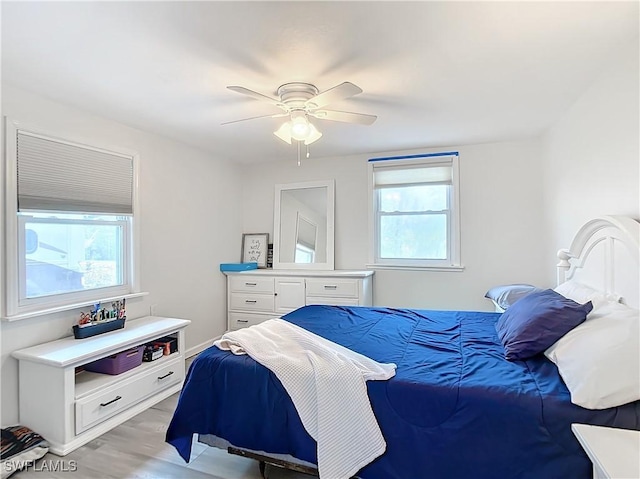 bedroom featuring ceiling fan, multiple windows, and light wood-type flooring