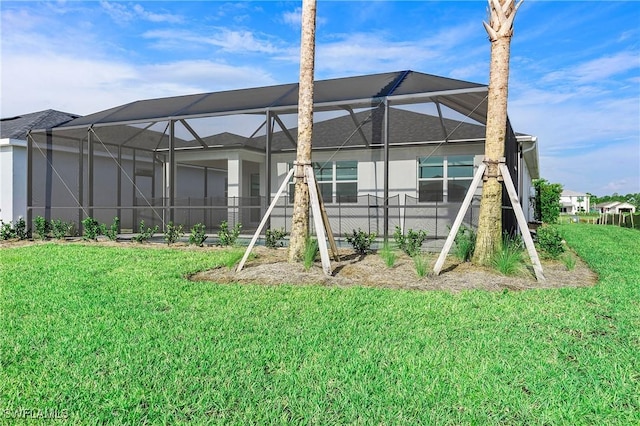 back of property featuring glass enclosure and a lawn