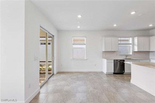 kitchen with sink, light tile patterned floors, dishwasher, decorative backsplash, and white cabinets