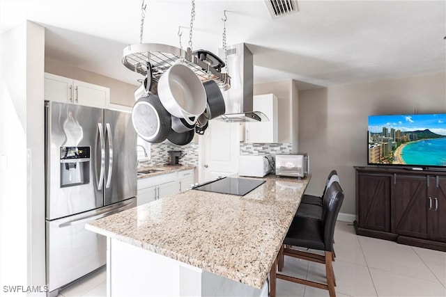 kitchen with sink, white cabinetry, stainless steel refrigerator with ice dispenser, island range hood, and black electric cooktop