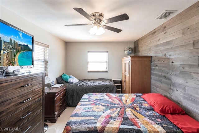 tiled bedroom featuring ceiling fan, multiple windows, and wood walls