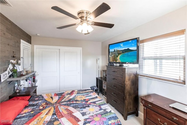 bedroom with ceiling fan, a closet, and wood walls