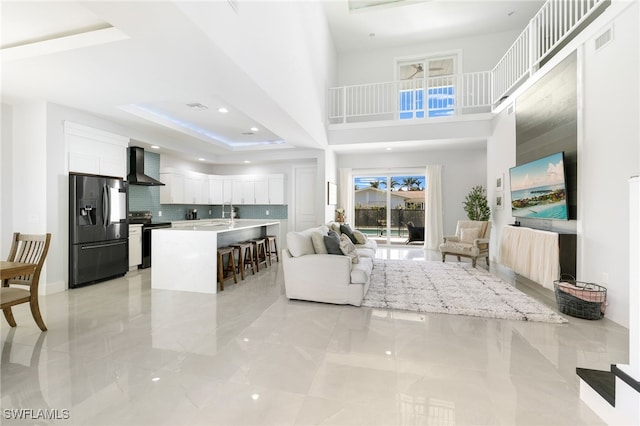 living room with a towering ceiling, a raised ceiling, and sink