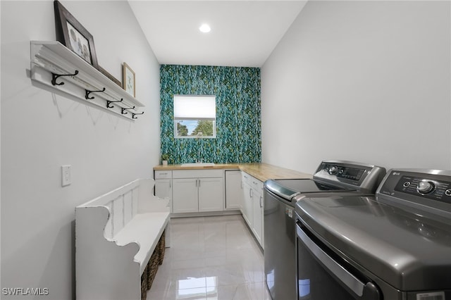 laundry room featuring light tile patterned flooring, cabinets, washer and clothes dryer, and sink